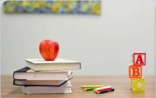 Stack of books with an apple and ABC blocks
